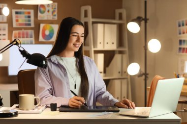 Akşam ofiste grafik tabletle çalışan kadın tasarımcı