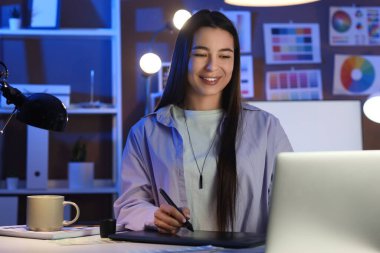 Akşam ofiste grafik tabletle çalışan kadın tasarımcı