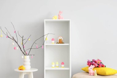 Şenlikli oturma odasının içinde raflar, puf, tavşanlar ve boyalı yumurtalar. Paskalya kutlaması