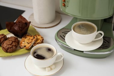 Modern kahve makinesi, mutfaktaki masada bir fincan kahve ve pasta. Yakın çekim.