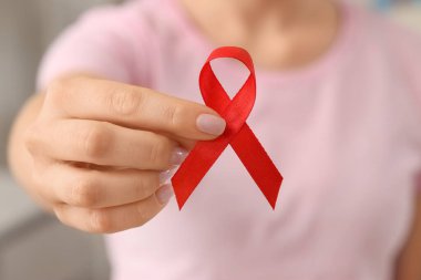 Klinikte kırmızı kurdeleli genç bir kadın, yakın plan. Kan kanseri farkındalığı kavramı
