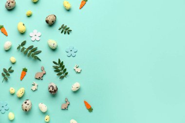 Yeşil yapraklı kompozisyon, Paskalya yumurtaları ve turkuaz arka planda dekoratif çiçekler.