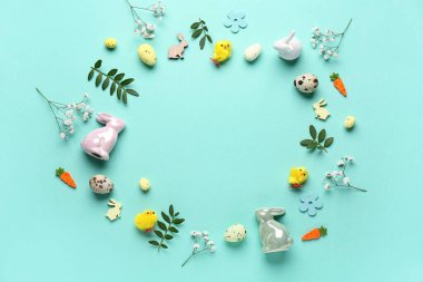 Frame made of Easter eggs, flowers and pussy willow branches on turquoise background