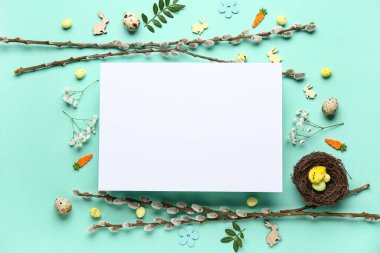 Composition with blank card, Easter eggs and pussy willow branches on turquoise background