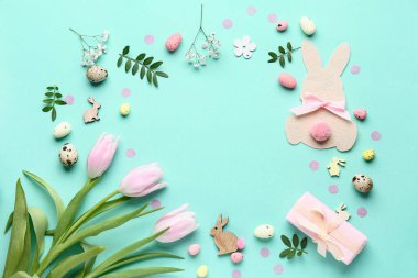 Kağıt tavşandan yapılmış çerçeve, Paskalya yumurtaları, çiçekler ve turkuaz arka planda hediye kutusu.