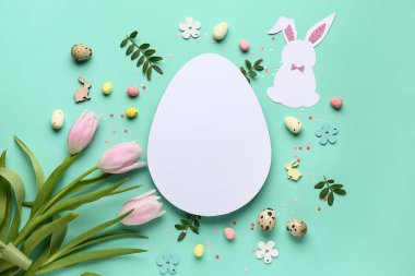 Kağıt tavşandan yapılmış çerçeve, Paskalya yumurtaları, çiçekler ve turkuaz arka planda boş kart.