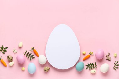 Yumurta şekilli boş kart, Paskalya yumurtaları, dekoratif havuçlar ve pembe arka planda yeşil yapraklar.