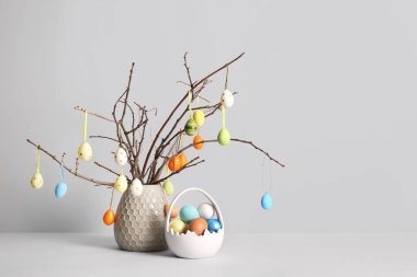 Ağaç dalları ve beyaz arka planda renkli Paskalya yumurtaları olan vazo.