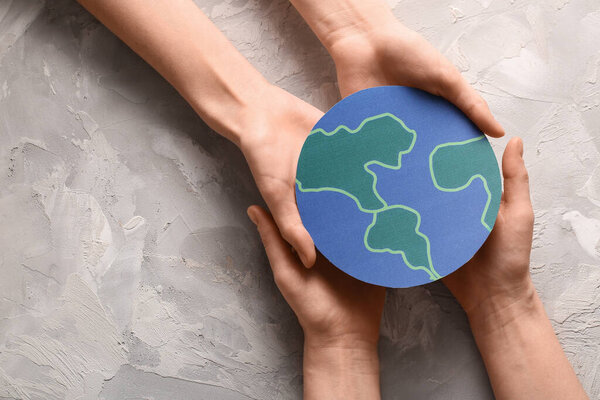 Женские руки с бумажной планетой на фоне гранжа. День Земли