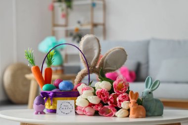 Tavşan kulaklı bir sepet Paskalya yumurtası, tebrik kartı ve oturma odasındaki güzel lale çiçekleri.