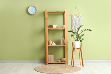 Kitaplı, dekorlu ve yeşil duvarlı raflar.