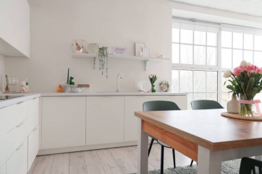 Paskalya için dekore edilmiş hafif mutfağın içinde yemek masası, raf ve tezgahlar var.