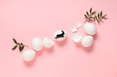 Pembe arka planda yumurta, kabuk ve bitki yapraklarıyla kompozisyon. Paskalya kutlaması
