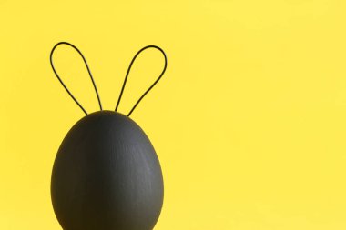 Sarı arka planda tavşan kulaklı yaratıcı Paskalya yumurtası, yakın plan.