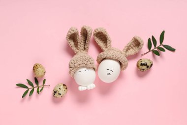 Komik Paskalya yumurtaları ve pembe arka planda bitki yapraklarıyla kompozisyon