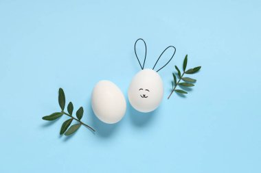 Komik Paskalya yumurtaları ve bitki yapraklarıyla renklendirilmiş kompozisyon