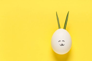 Sarı arka planda tavşan kulaklı komik bir Paskalya yumurtası.