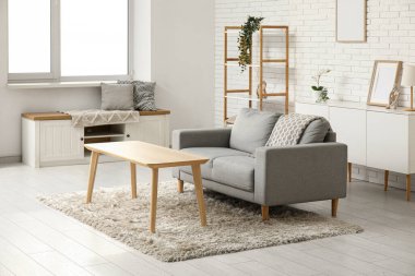 Oturma odasının içinde kanepe, raf ünitesi, çekmeceler ve masa var.