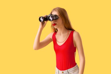 Sarı arka planda dürbünlü genç bayan cankurtaran.