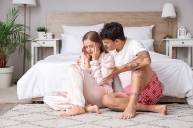 Baş ağrısı olan genç bir kadın ve kocası yatak odasında. Cinsel sorunlar kavramı