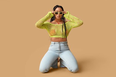 Bej arka planda örgüleri olan seksi Afro-Amerikalı kadın.