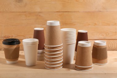 Ahşap arka planda farklı tek kullanımlık kahve fincanları.