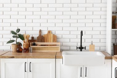 Mutfaktaki beyaz tuğla duvarın yanındaki tezgahlara lavabo ve bitki döşemek.