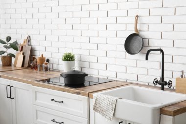 Mutfak tezgahları soba, çatal bıçak ve lavabo beyaz tuğla duvarın yanında.