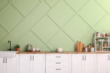 Modern mutfağın içinde lavabo, mutfak gereçleri ve elektrikli soba var.