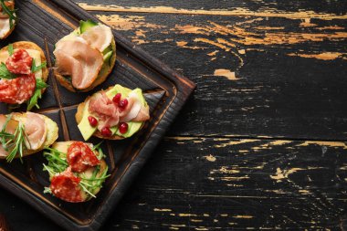 Koyu ahşap arka planda jambonlu lezzetli bruschettalar, yakın plan.