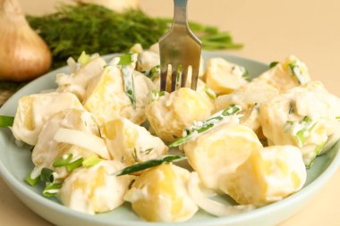 Sarı arka planda yeşil salatalı lezzetli patates salatası, yakın plan.