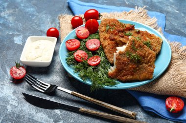 Mavi arka planda soslu kızarmış morina balığı tabağı.