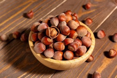 Ahşap arka planda kabuklu fındıklı kase