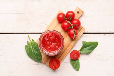 Hafif ahşap arka planda lezzetli domates soslu kavanoz.