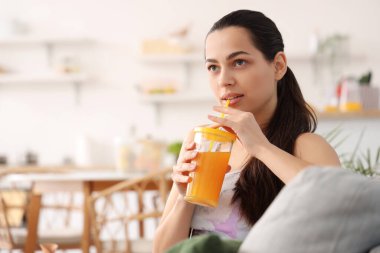 Mutfakta sebze suyu içen genç bir kadın.