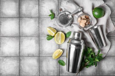 Siyah kiremit arkaplan üzerine mojito hazırlamak için sallayıcı, süzgeç ve malzemeler