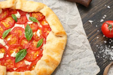 Lezzetli domates galeti ve ahşap arka planda fesleğen içeren kağıt fırını.