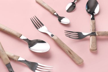 Pembe arka planda şık çatallar ve kaşıklar