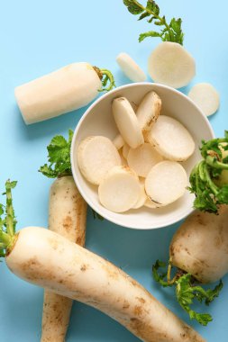 Mavi arka planda taze daikon turpu dilimleri ile kase