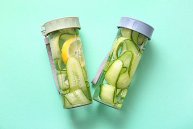 Turkuaz arka planda salatalık dilimli spor şişeleri.