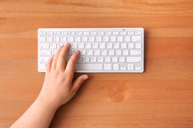 Tahta masadaki bilgisayar klavyesini kullanan kadın programcı