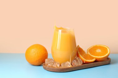 Tahta ve bir bardak taze portakal suyu. Masada bej arka planda lekeler var.