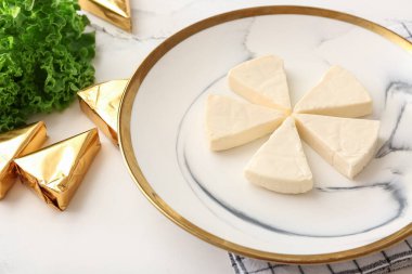 Açık arkaplanda lezzetli işlenmiş peynir üçgenleri olan tabak, yakın plan.