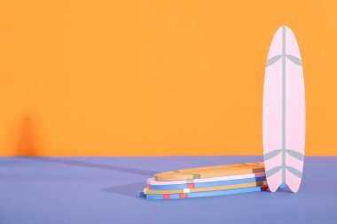 Mavi masada turuncu arka planda bir sürü renkli sörf tahtası var.