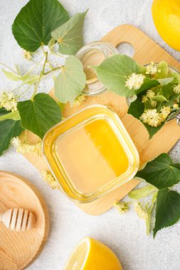Tahta tahta tahta, beyaz arka planda bir kase ıhlamur, bal ve limon.