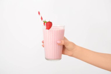 Beyaz arka planda bir bardak lezzetli çilekli smoothie tutan kadın.