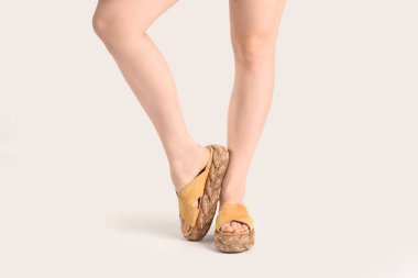 Beyaz arka planda parmak arası terlik giymiş kadın bacakları