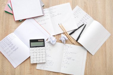 Matematik formülleri ve ahşap masadaki kırtasiye malzemeleriyle metin kitaplarını aç