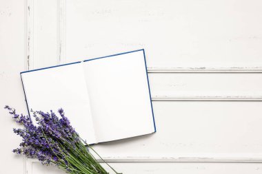 Güzel lavanta çiçekleri ve açık ahşap zemin üzerine boş bir kitap.