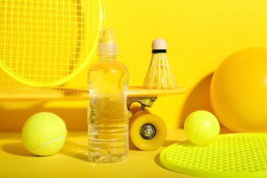 Sarı arka planda su şişesi olan spor ekipmanları.